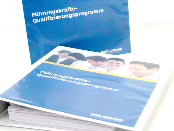 Zwei Ordner gefüllt mit Programmen zur Qualifizierung für Führungskräfte.